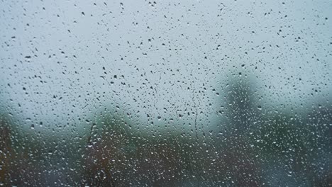 lluvia golpeando la ventana y goteando en un día nublado con fondo borroso