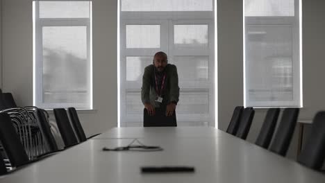 nervous asian manager alone in empty meeting room waiting for colleagues