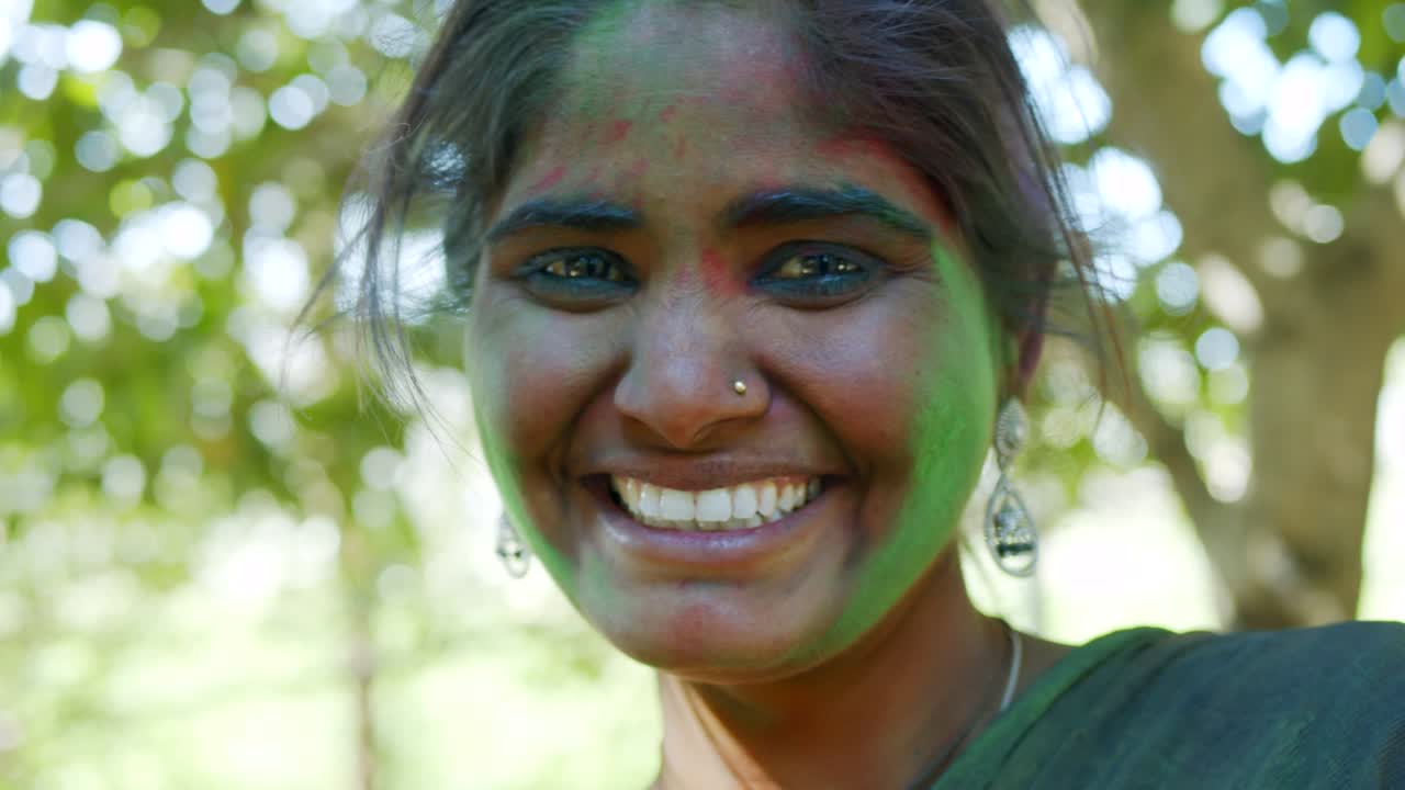인도 여성의 가까운 얼굴은 밝은 홀리 색으로 얼룩져 있습니다.