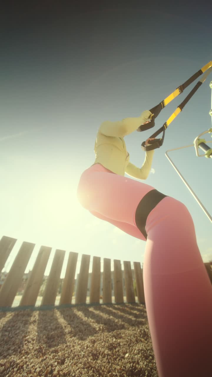 Woman exercising outdoors with suspension trainer