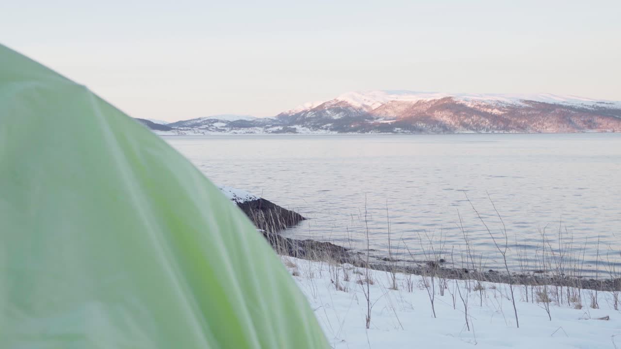 캠핑 텐트는 겨울 일출 동안 호수의 잔잔한 물을 드러냈다