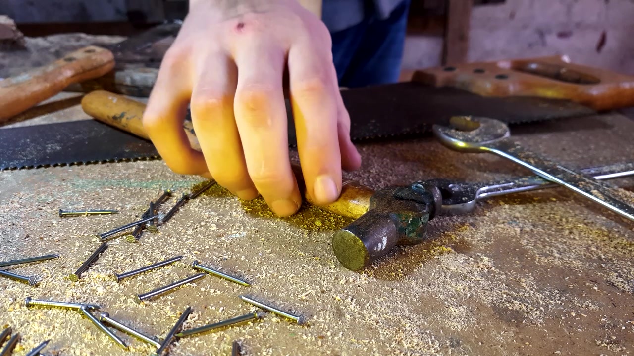 Mysterious person grabs a hammer off of a workbench. Is it being used as a tool or as a weapon?
