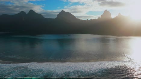 morning sunrise blue sky sun flare moorea island cooks opunohu bay french polynesia aerial drone lagoon coral reef mount mauaroa tohivea rotui jagged peaks haapiti paopao pacific ocean upwards