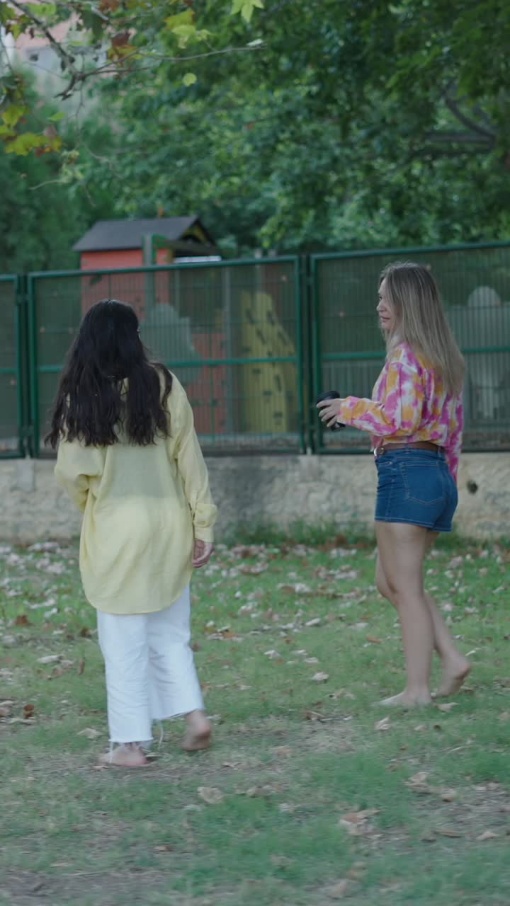 Two women walking barefoot in a park