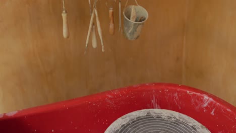 pottery equipment and hanging tools with handmade pots and plates lying on shelf in pottery workshop