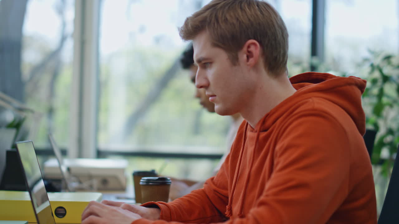 개발자가 작업장에서 노트북을 코딩하는 클로즈업. 팀이 함께 일합니다.