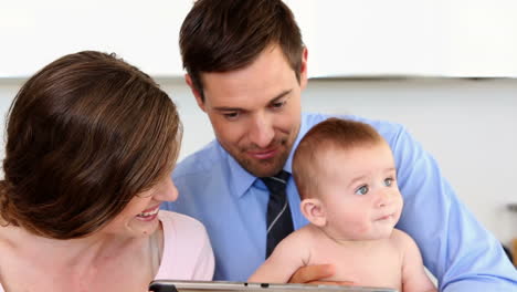 happy parents using tablet pc with their baby son in the morning
