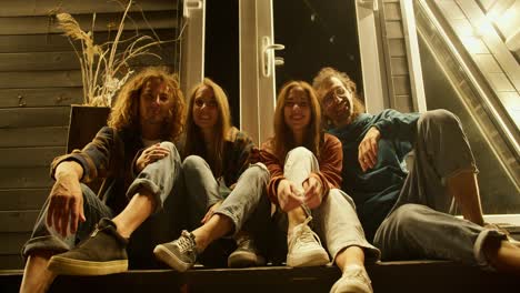 portrait: a company of two couples sitting at the entrance to the house and hugging. rest at the party. rest in the country house