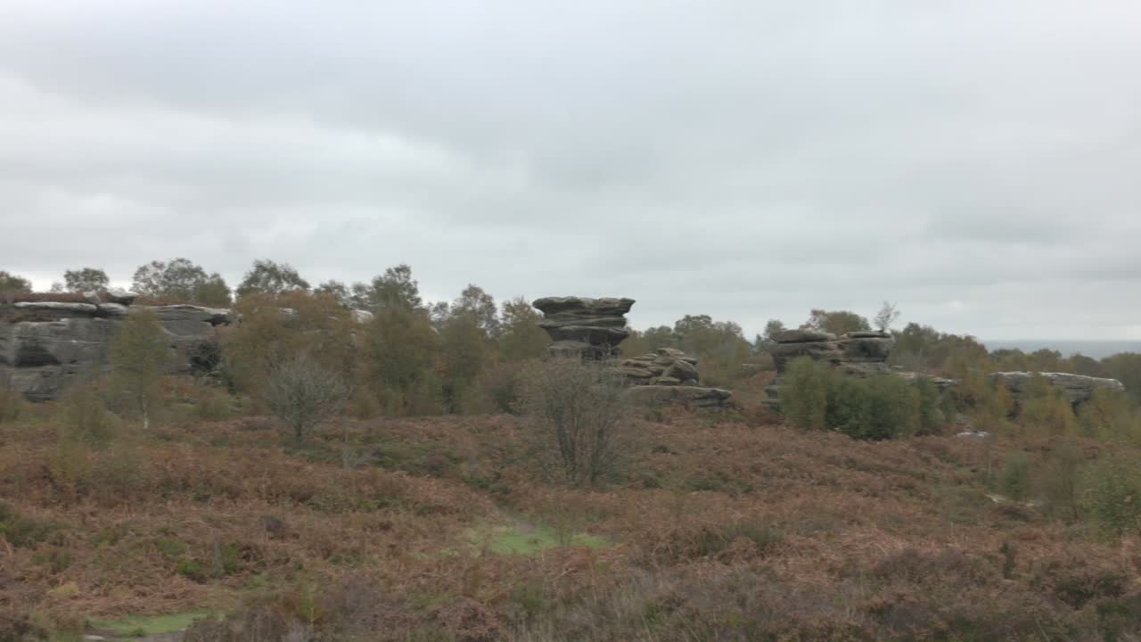 Panorering af store klippeformationer med turister ved Brimham Rocks