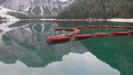 aerial shot from drone around aligned boats in braies lake in the dolomites, italy