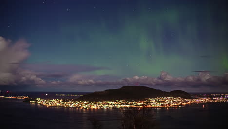 high angle shot of city along the alesund island, norway with the view of northern lights in timelapse, visible at night time