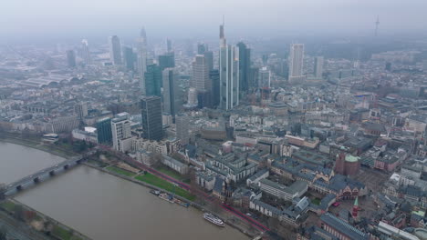 Luftpanoramaaufnahmen-Der-Stadt-Mit-Hochhäusern-Im-Geschäftszentrum.-Dunstiger-Blick-Auf-Die-Großstadt.-Breiter-Fluss-Ruhig-Fließend.-Frankfurt-Am-Main,-Deutschland