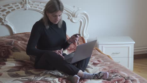 a woman sits on her bed and makes purchases online using a bank card. electronic commerce.