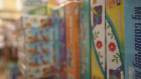 a dolly shot tracking backwards across a store shelf packed with different board games and puzzles in a toy shop