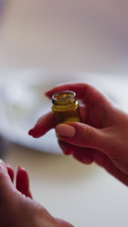 persona femenina abre y agita una pequeña botella de vidrio de polvo soporífico planeando envenenar y robar al amante en la cena en casa closeup cámara lenta