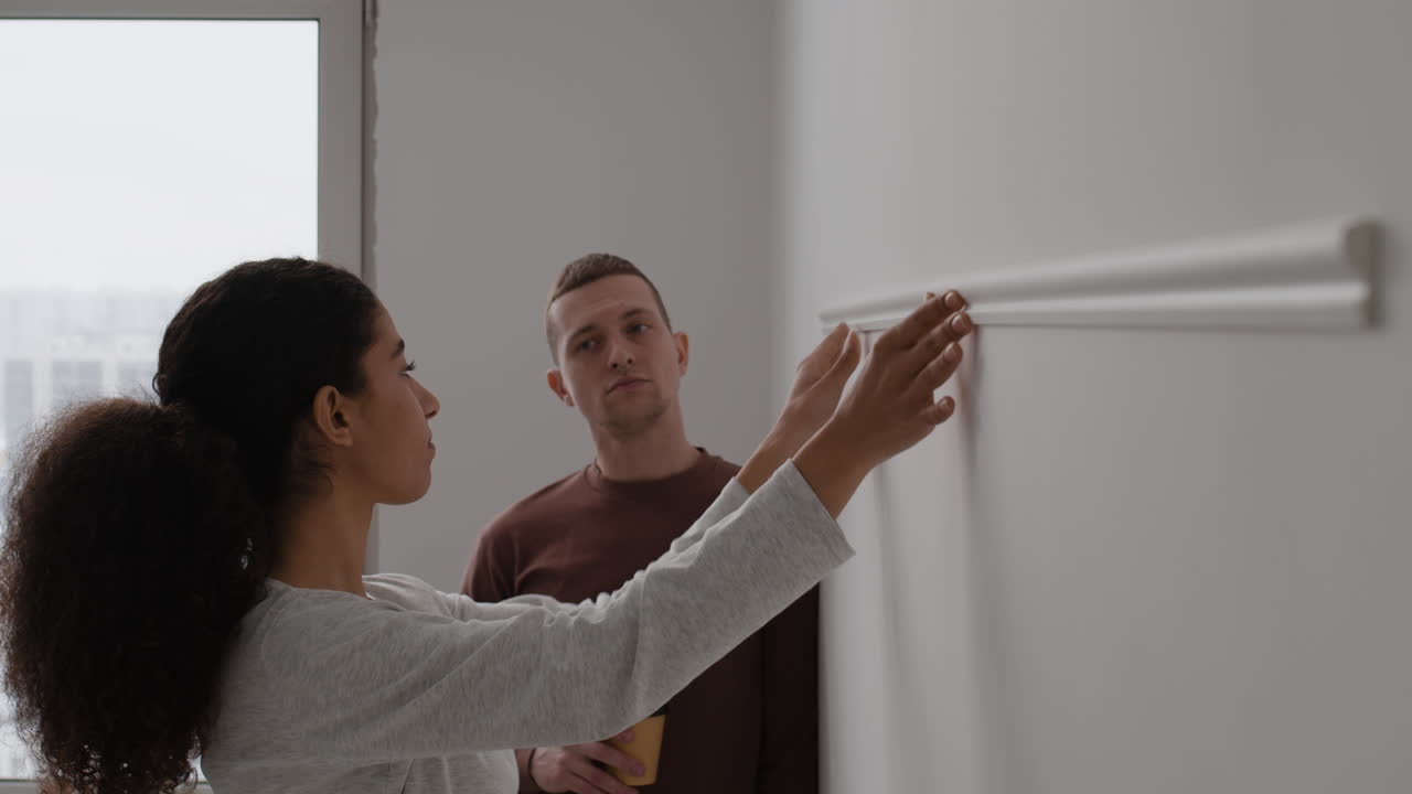 Couple Installing Crown Molding on White Wall