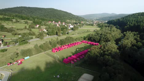 aerial view of red picnic tents crammed on football pitch on sunny day