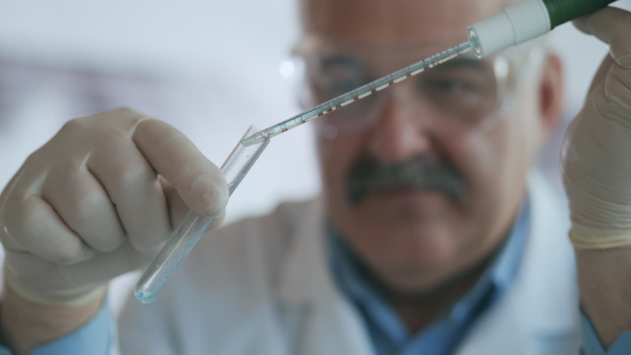 Technician carefully drips the solution from the pipette into glass tubes for DNA analysis. Doctor Drips Blue Solution Into Glass Tube Coronavirus Pandemic Hands Closeup. High quality 4k footage