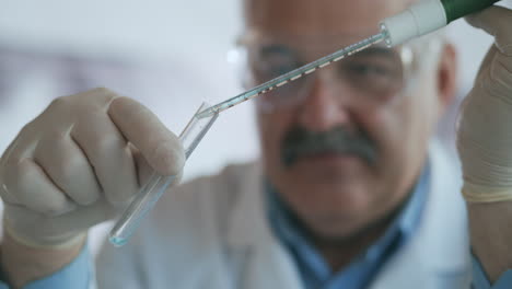 technician carefully drips the solution from the pipette into glass tubes for dna analysis. doctor drips blue solution into glass tube coronavirus pandemic hands closeup. high quality 4k footage