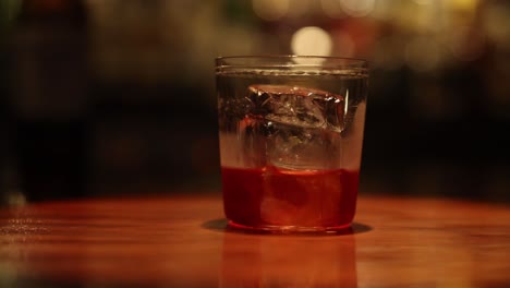 un vaso de whisky con hielo en una barra