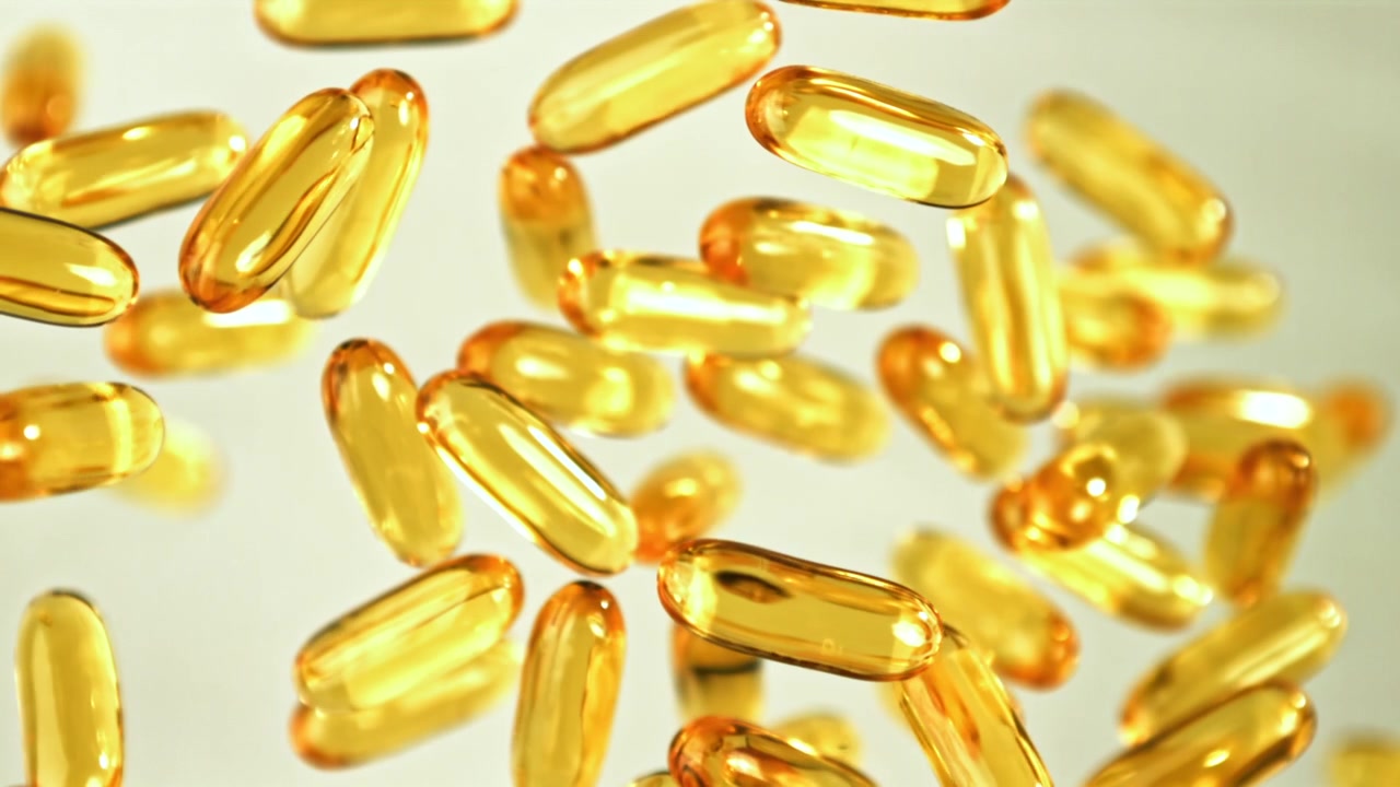 Capsule dorate di Omega 3 che cadono al rallentatore.