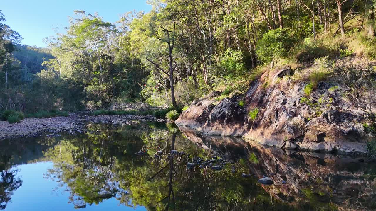Tranquil river scene with lush greenery and rocky banks, captured in natural daylight with gentle camera movement