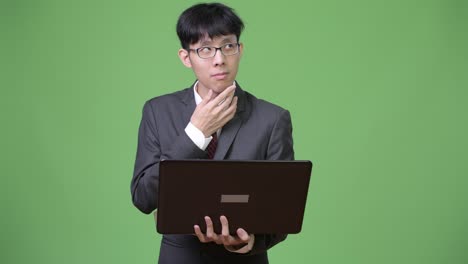 젊은 아시아 사업가 가 노트북 을 사용 하면서 생각 하고 있다