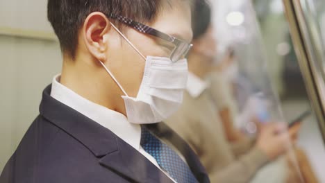 traveler wearing face mask while using mobile phone on public train