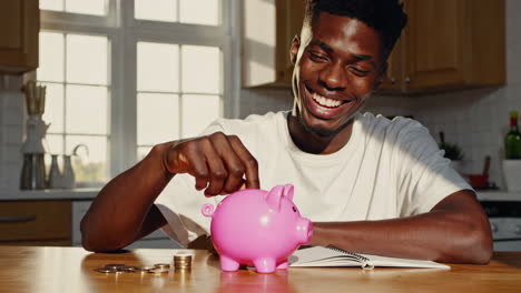 young man joyfully saving money in a pink piggy bank
