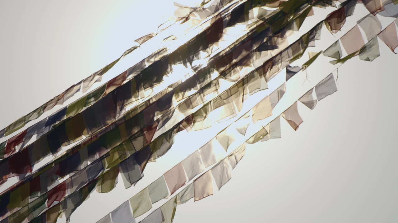 A Buddhist flag glows beautifully under the setting sun in Nepal. As the sky turns golden, the flag waves gently, symbolizing peace, faith, and the calm spirit of Buddhist devotion