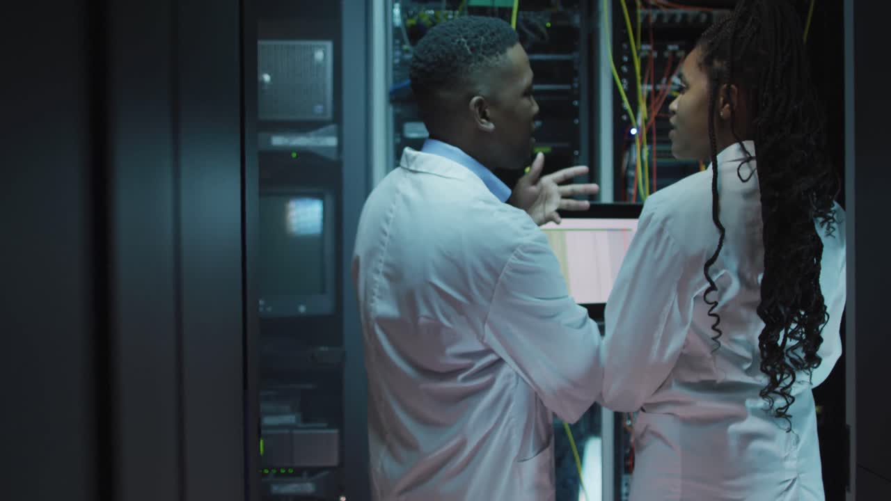 técnicos de computadoras afroamericanos usando computadoras portátiles trabajando en la sala de servidores de negocios