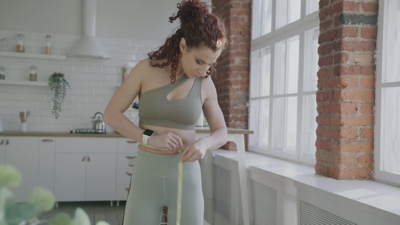 Woman Measuring Waist in Kitchen