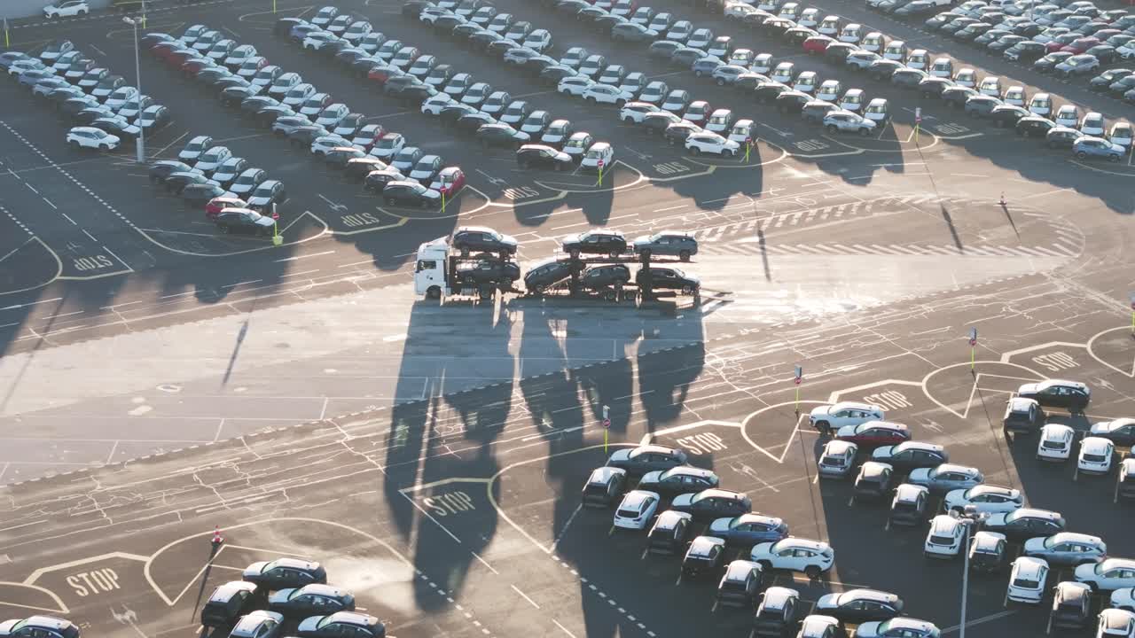 Car carrier trailer with cargo parked in sunny manufacturing plant yard