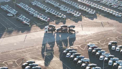 car carrier trailer with cargo parked in sunny manufacturing plant yard