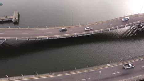 Aerial-drone-tilt-down-view-of-Leonel-Viera-unusual-wavy-shaped-bridge-with-cars-trucks-and-motorcycles-crossing-river-Arroyo-Maldonado-in-Uruguay