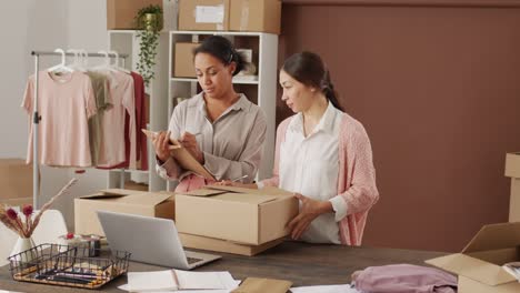 and businesswomen work in their online shop organizing boxes in warehouse