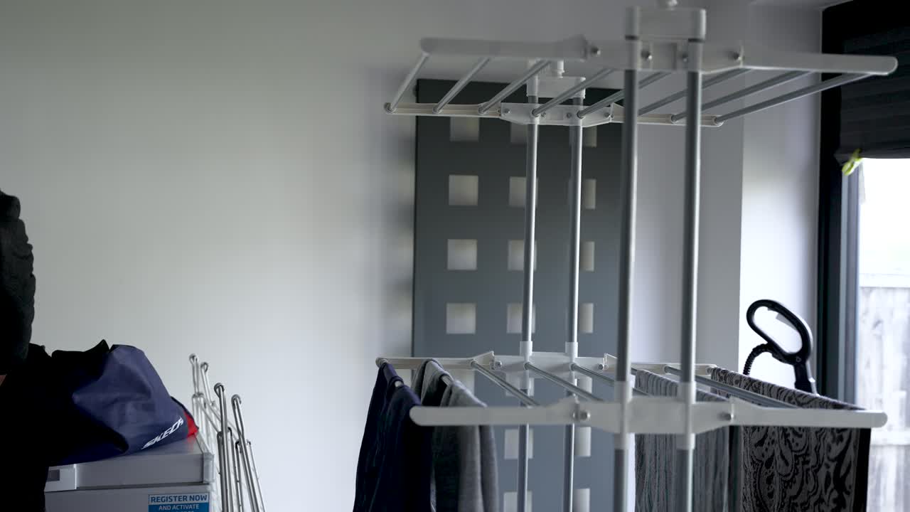 hombre en un hogar sacudiendo las arrugas de la camisa húmeda antes de ponerse el aireador interior en casa