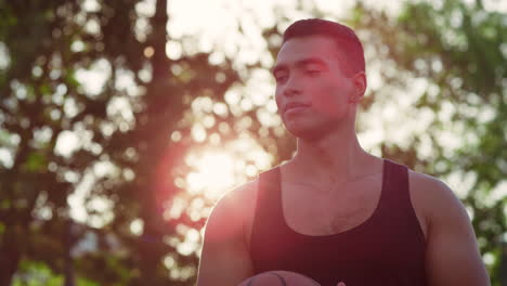 Portrait-of-sporty-mixed-race-man-practicing-street-basketball-outdoor.