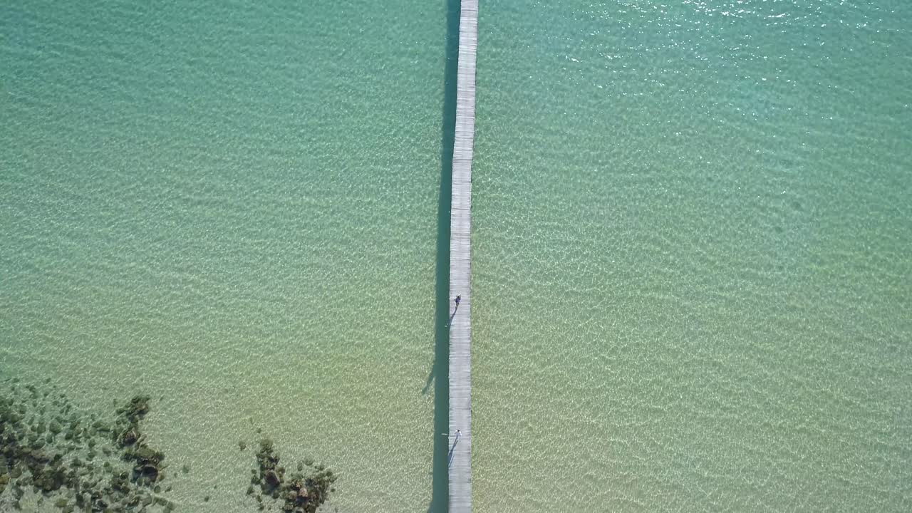 공중, 위에서 아래로, 새의 눈, 무인 항공기가 걷는 여자와 목조 부두에서 달리는 남자, 사람들이 청록색 바다, 낙원 해변, 맑은 날, 코 쿠드, 태국, 아시아에서 수영하는 동안