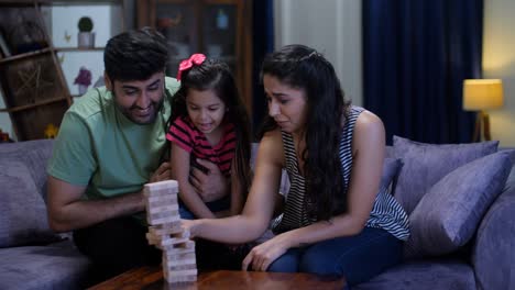 un marido y una esposa indios y su pequeña hija jugando a los bloques de construcción - crianza feliz, familia nuclear, padres jóvenes cariñosos