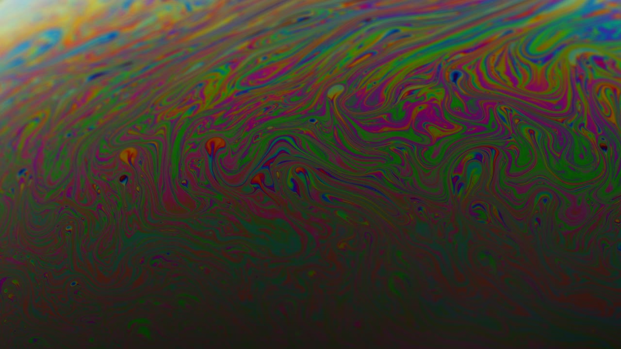 superficie del jabón en primer plano con rayas de arco iris y líneas en movimiento giratorio