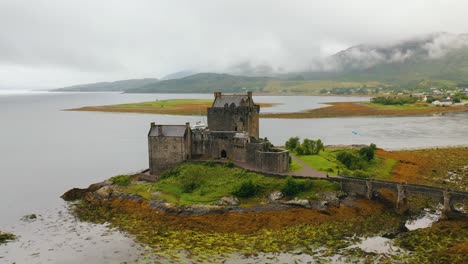 Aerial-Pan-of-Landmark-in-Scotland,-Eilean-Donan-Castle-in-the-Scottish-Highlands-on-Loch-Duich-on-Low-Tide,-Scotland,-United-Kingdom