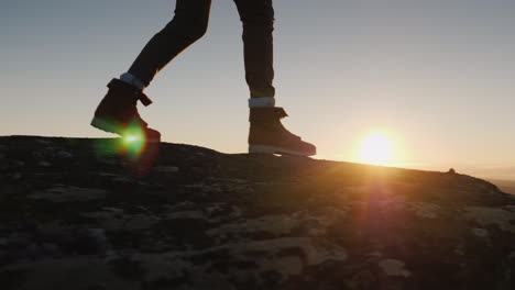 las piernas caminan al borde de la tierra del cielo y el sol caminando en las montañas de noruega