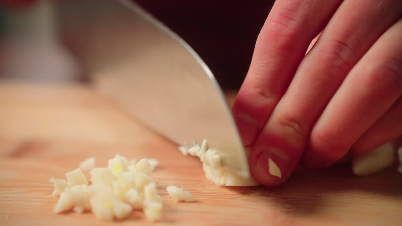 Slicing garlic by hand with a knife on a cutting board