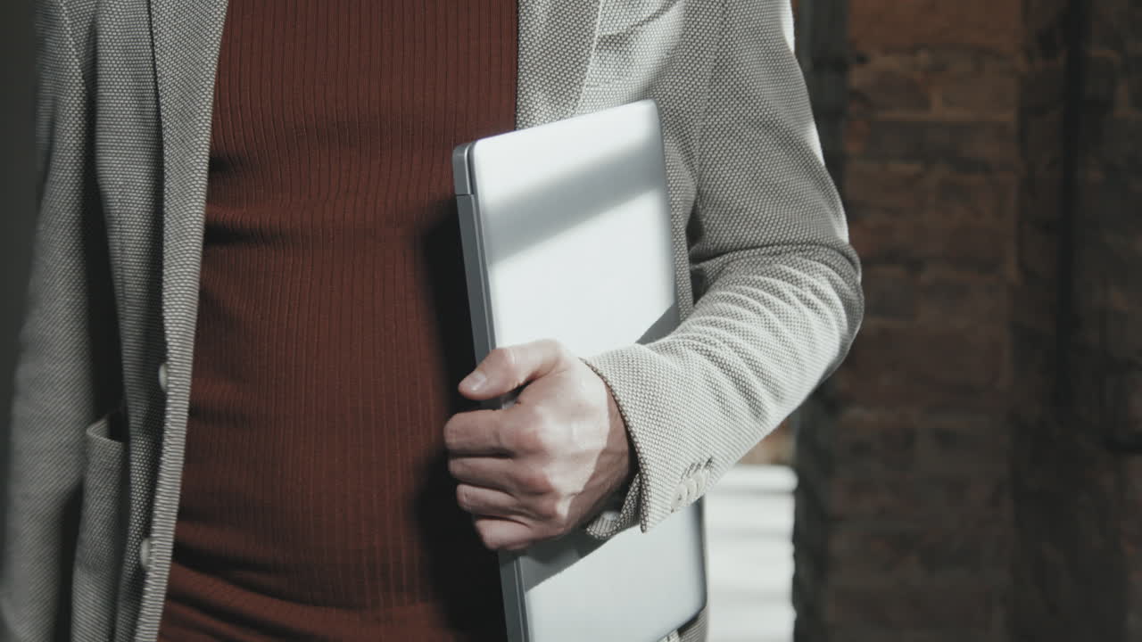 Mid-Section of Businessman with Laptop Walking through Office