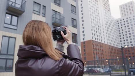 mujer tomando fotos de edificios de apartamentos modernos