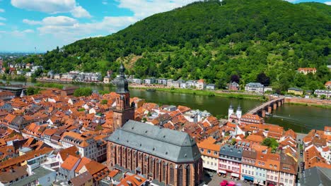 4k aerial drone video of the beautiful heiliggeistkirche church along the neckar river in heidelberg, germany