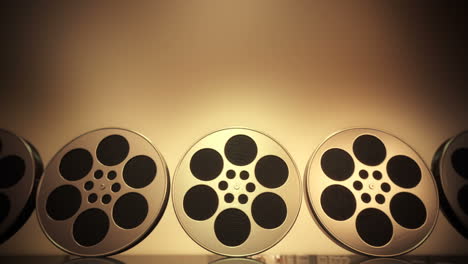 film-rolls rolling constantly from right to left. perfect background in full hd 1080p. film production studio. side view perspective. reflective surface. brownish background. loopable. hd