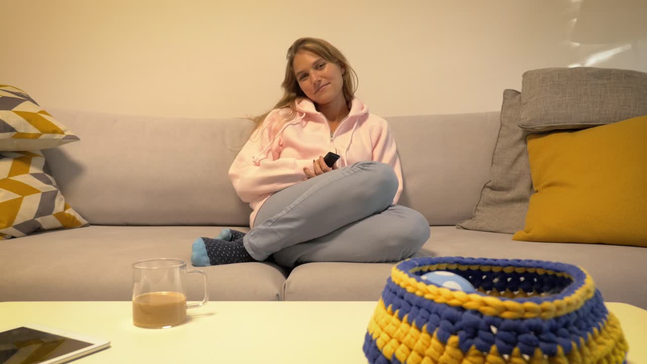 그녀의 아늑한 집에서 소파에 점프하고 tv에 turb에 리모콘을 누르십시오