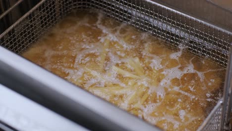 french fries are fried in a large pot. close up.